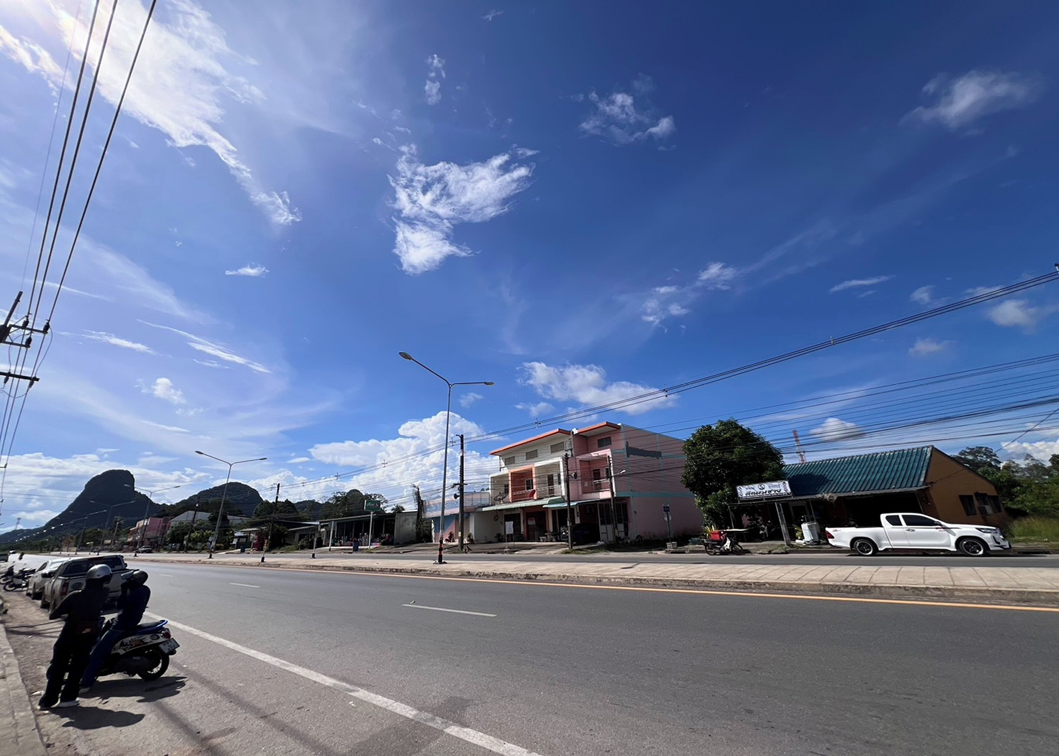 A street view with buildings, a clear sky, and a mountain in the background.