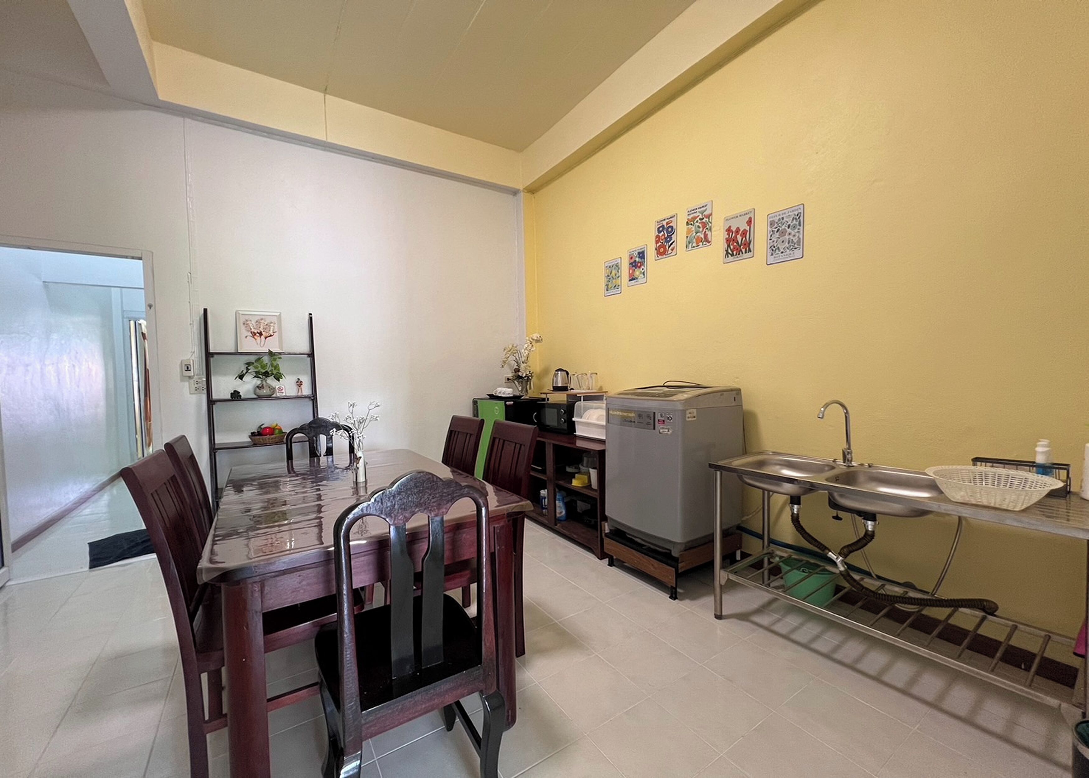 A compact kitchen with a dining table, chairs, a refrigerator, and a sink.