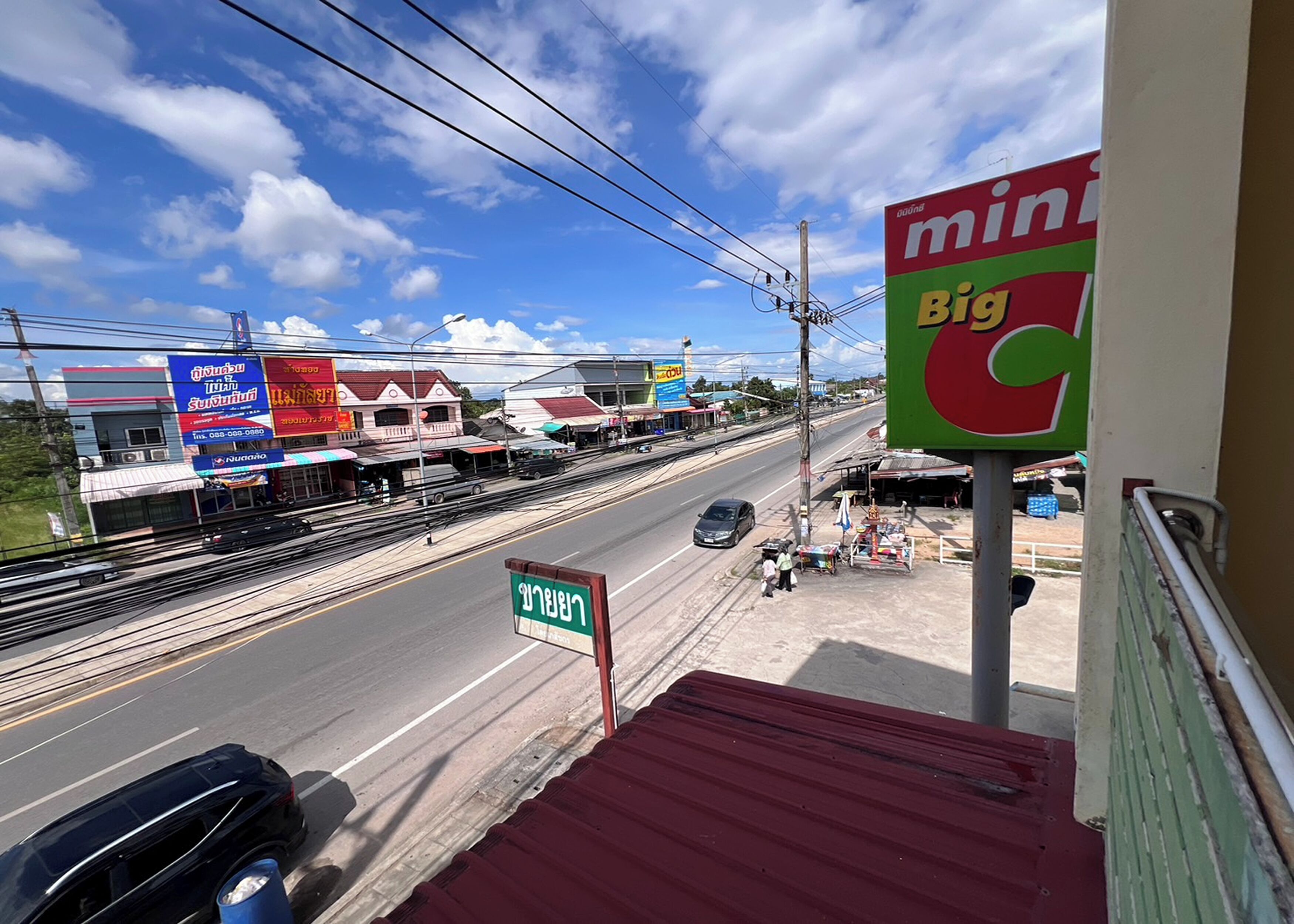 A street view with a Min Big C sign, a traffic light, and a green signboard.