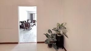 A hallway with a door leading to a dining area. There are potted plants on a small table and a chair. - Kuan Mapraw Villa 3 (Phatthalung)