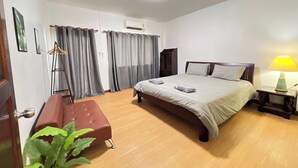 A hotel room with a bed, bedside table, lamp, and a plant. - Kuan Mapraw Villa 3 (Phatthalung)