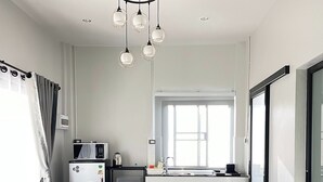 Et moderne køkken med spiseplads, der inkluderer et træbord, grå stole og et bord med glasplade samt en vase.