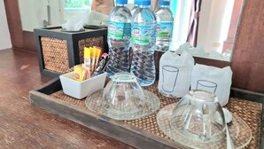 A tray with water bottles, a glass carafe, a sugar container, and a glass carafe on a woven mat. - Baan Bonsuan Hill Guesthouse (Kathu)