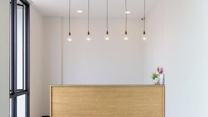 Un comptoir d’accueil avec un revêtement en bois, un plateau en verre et une petite plante placée sur le côté droit.