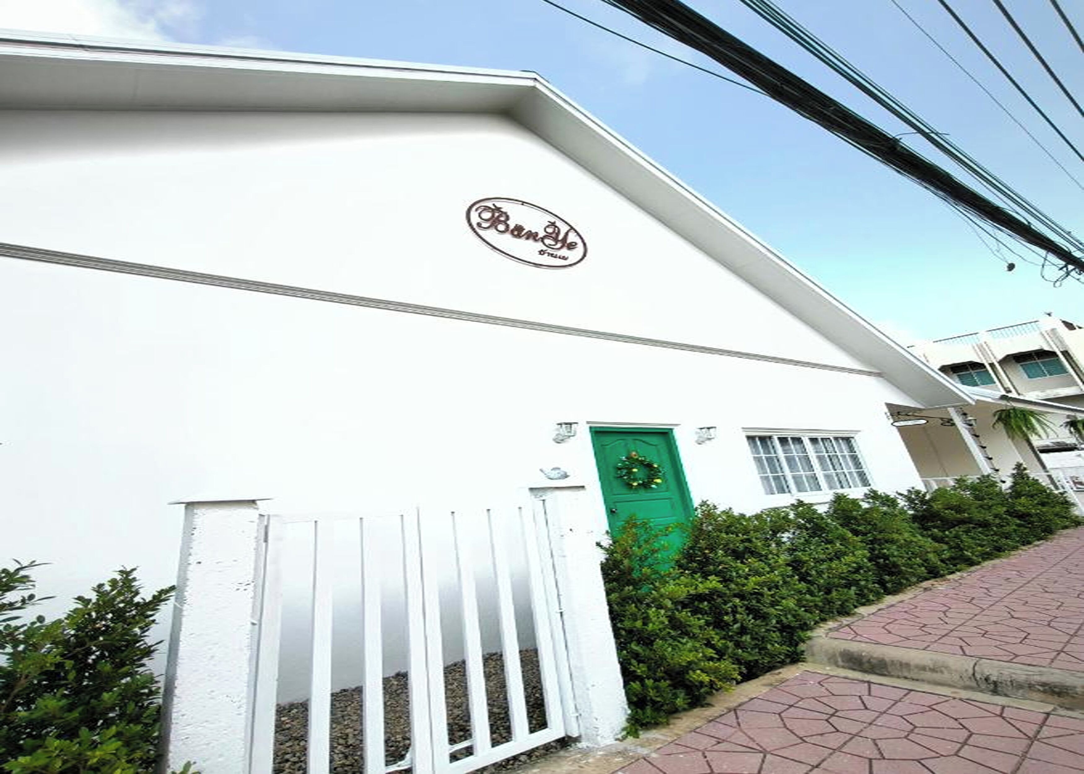 A building with a white facade, a green door, and a white gate.