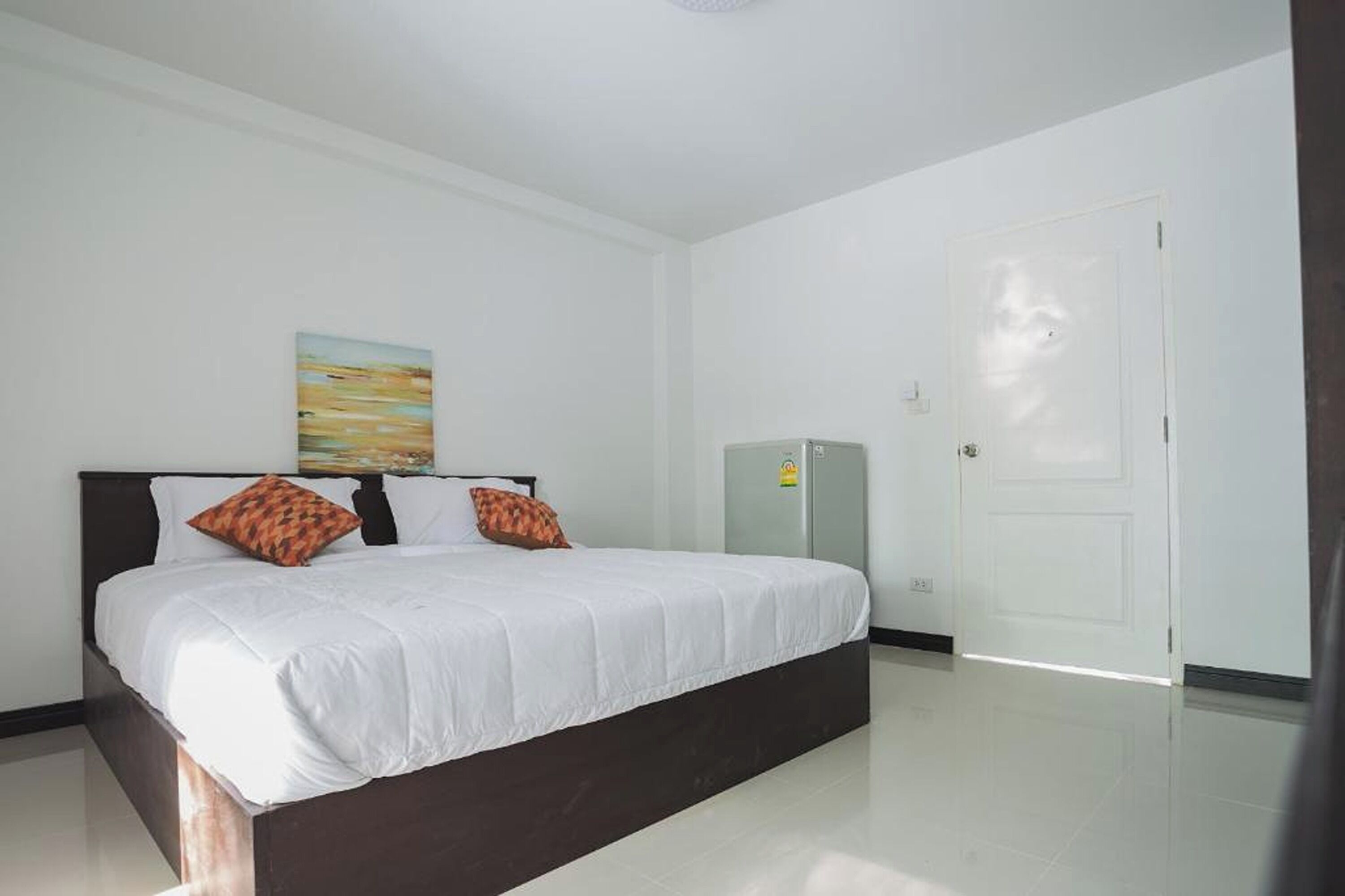 Un dormitorio con una cama grande, paredes blancas y una puerta.