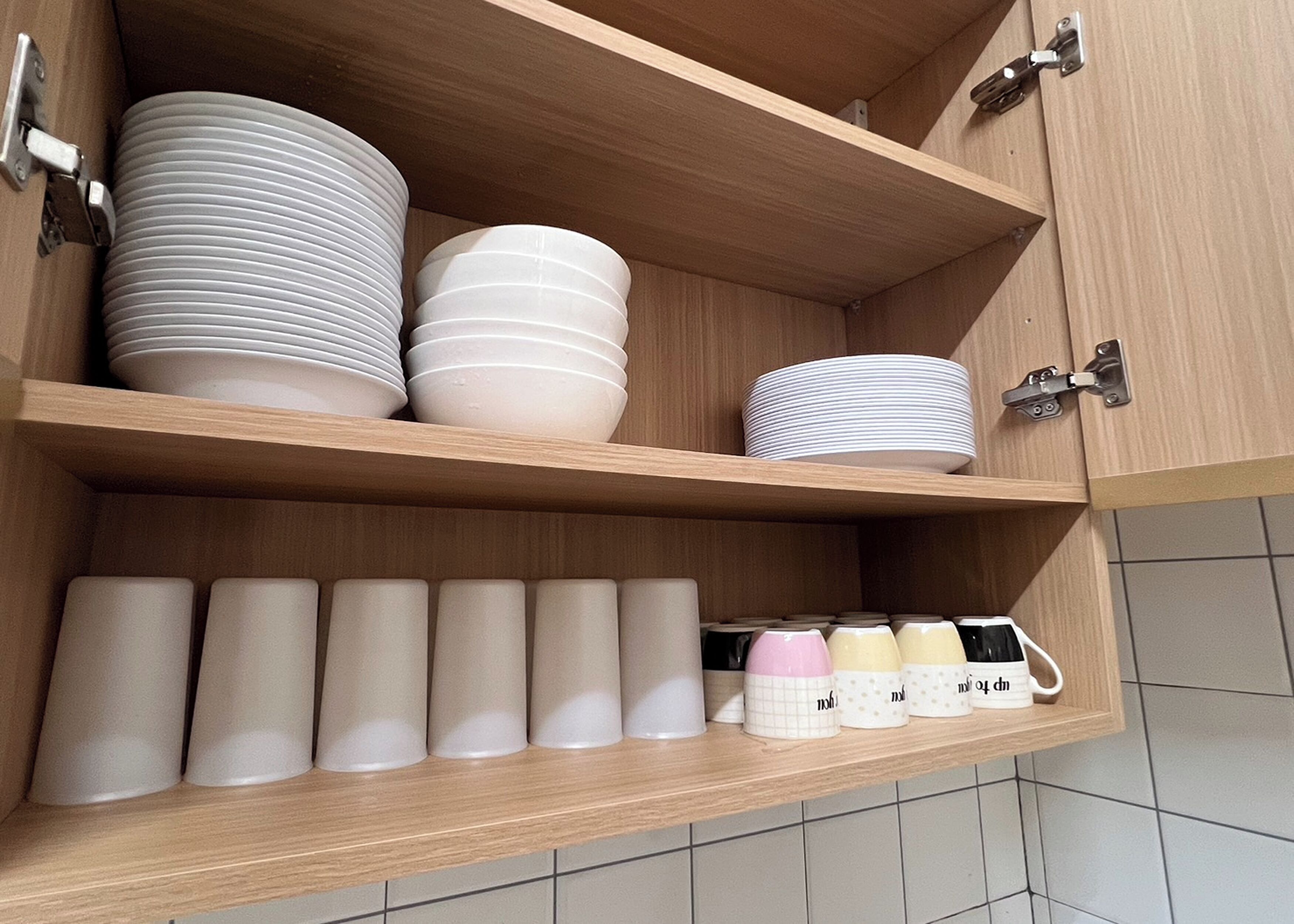 Un armario de cocina con varios estantes que contienen platos y tazas.