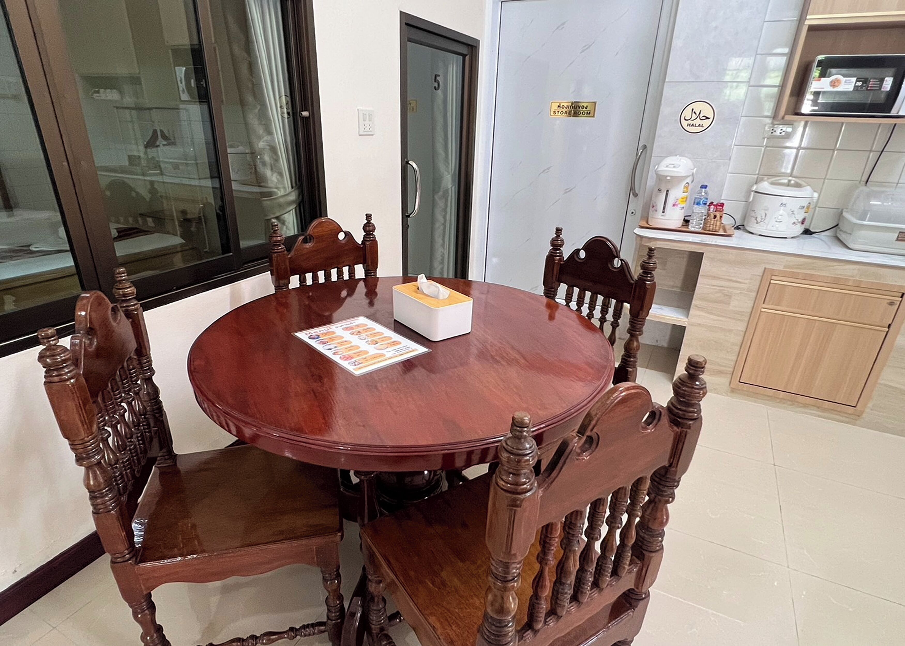 A dining area with a round wooden table and four chairs, a tissue box, and a menu.