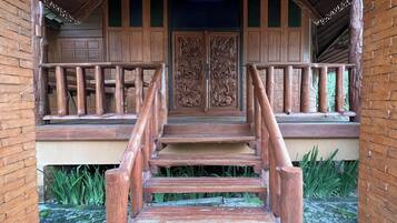 A wooden staircase leading to a porch with a decorative door and a railing.