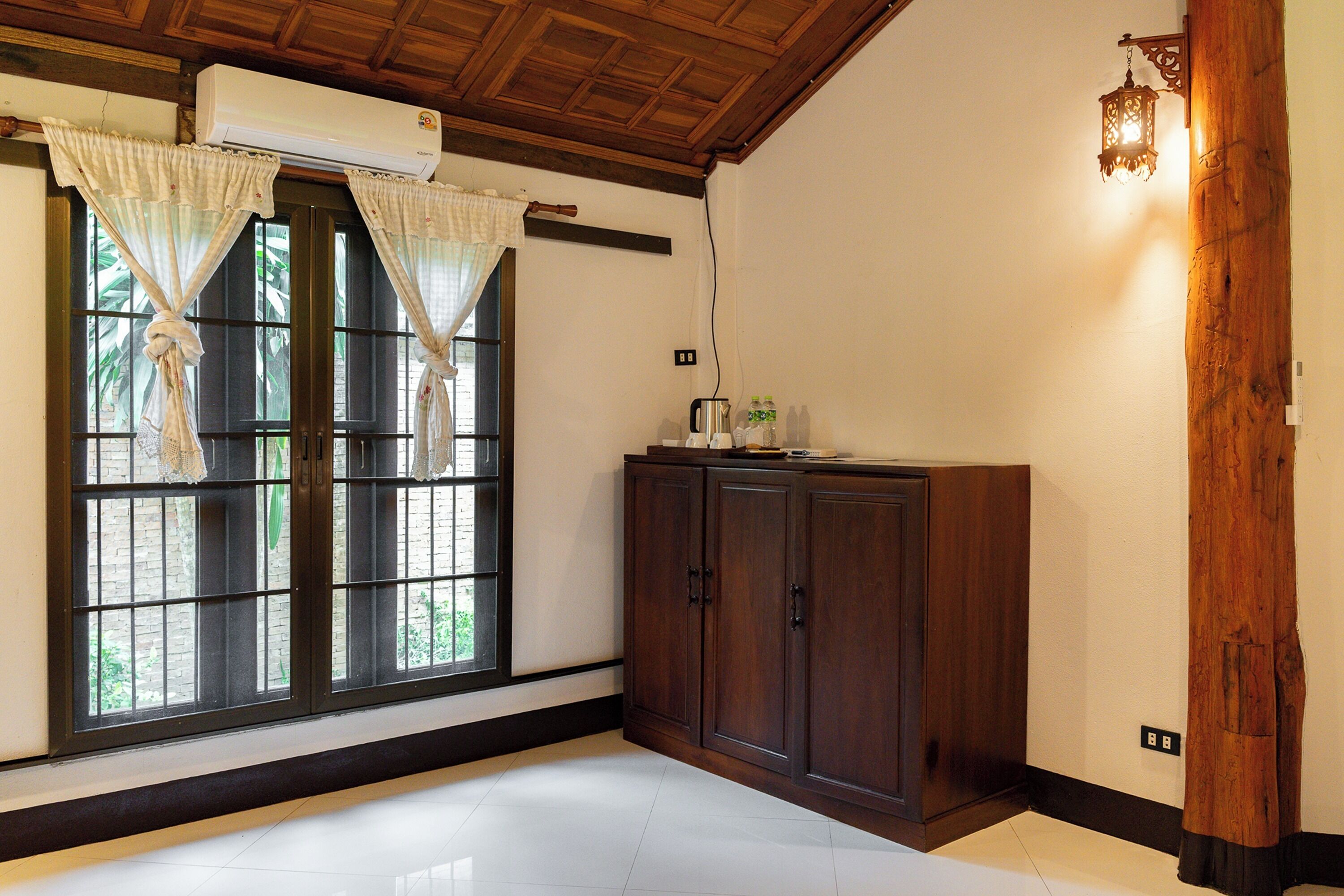 A room with a large window, wooden ceiling, and a cabinet.