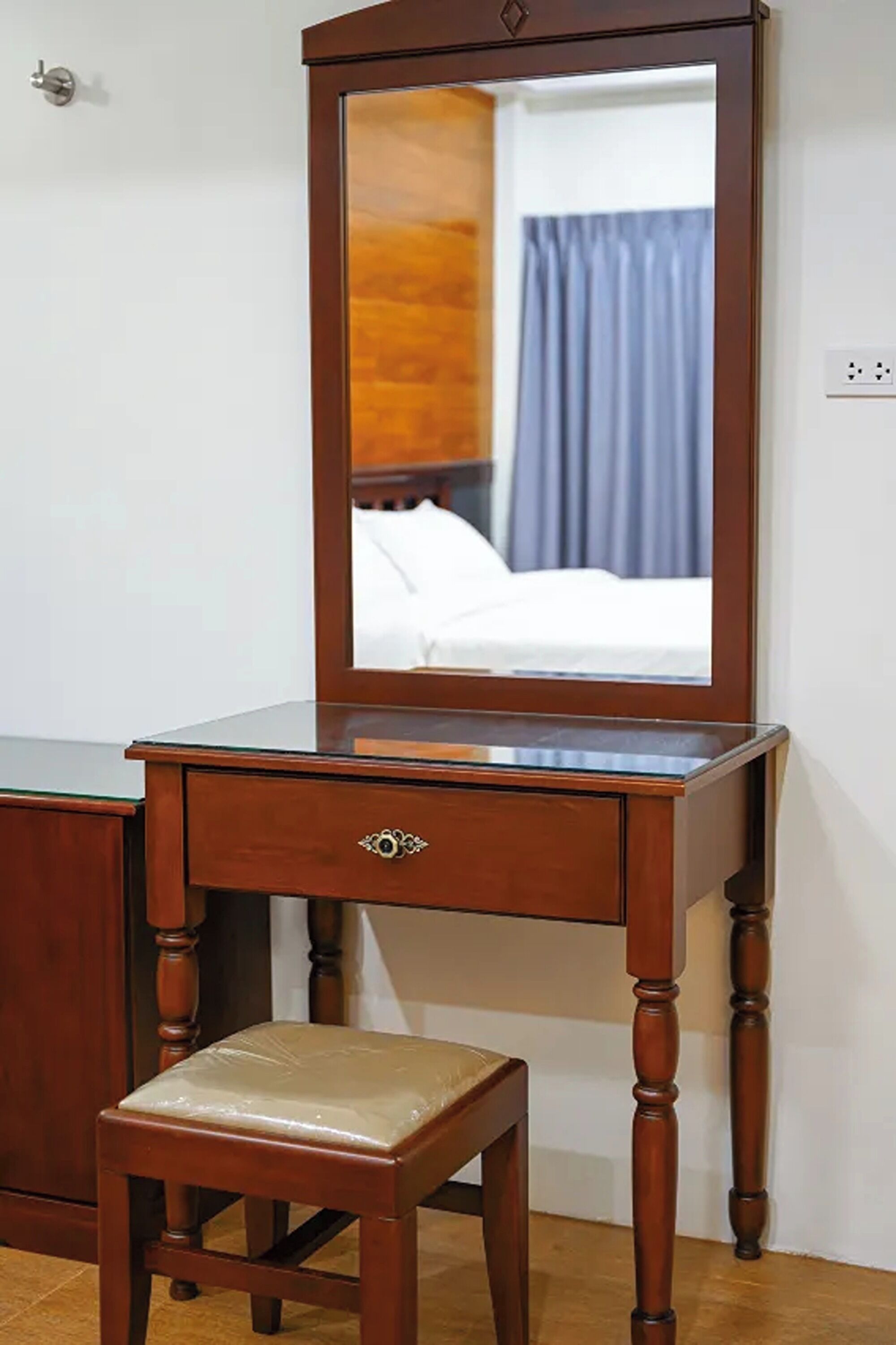 Une commode en bois avec un miroir, un tiroir et un tabouret.