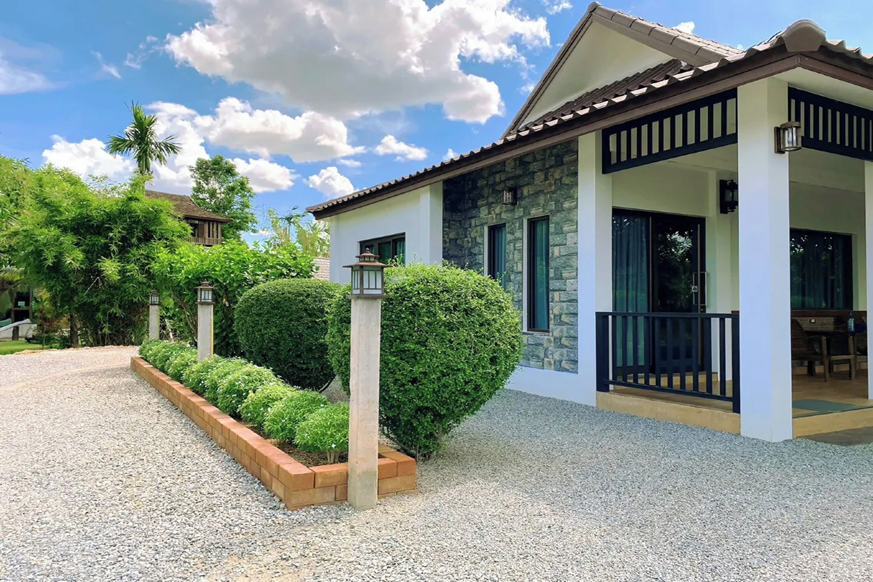 A two-story house with a stone facade, a balcony, and a gravel driveway.