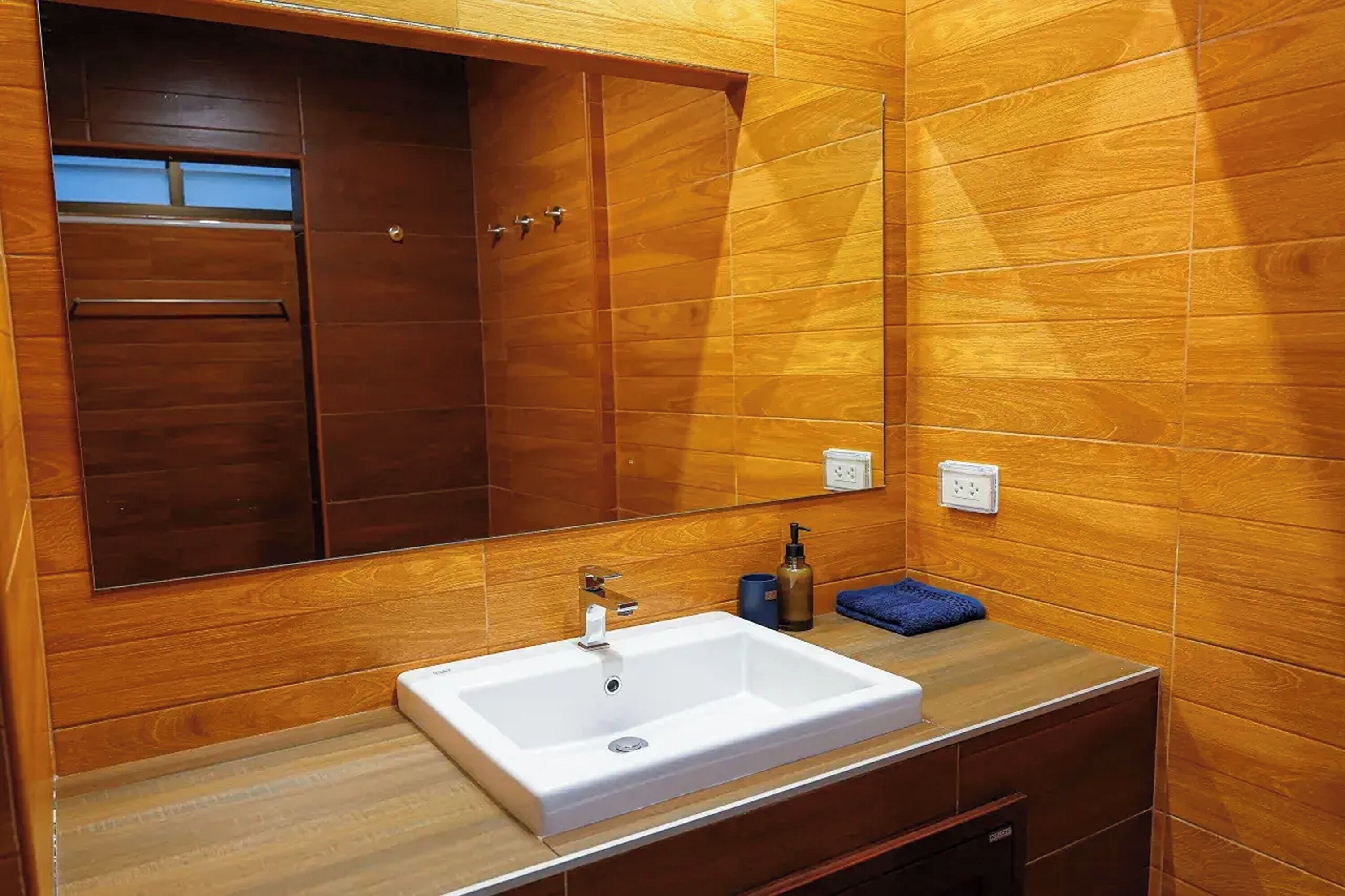 Une salle de bain avec un meuble-lavabo en bois, un lavabo blanc et un grand miroir.
