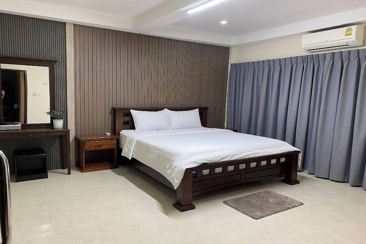 A neatly arranged bedroom with a bed, bedside table, and a mirror.