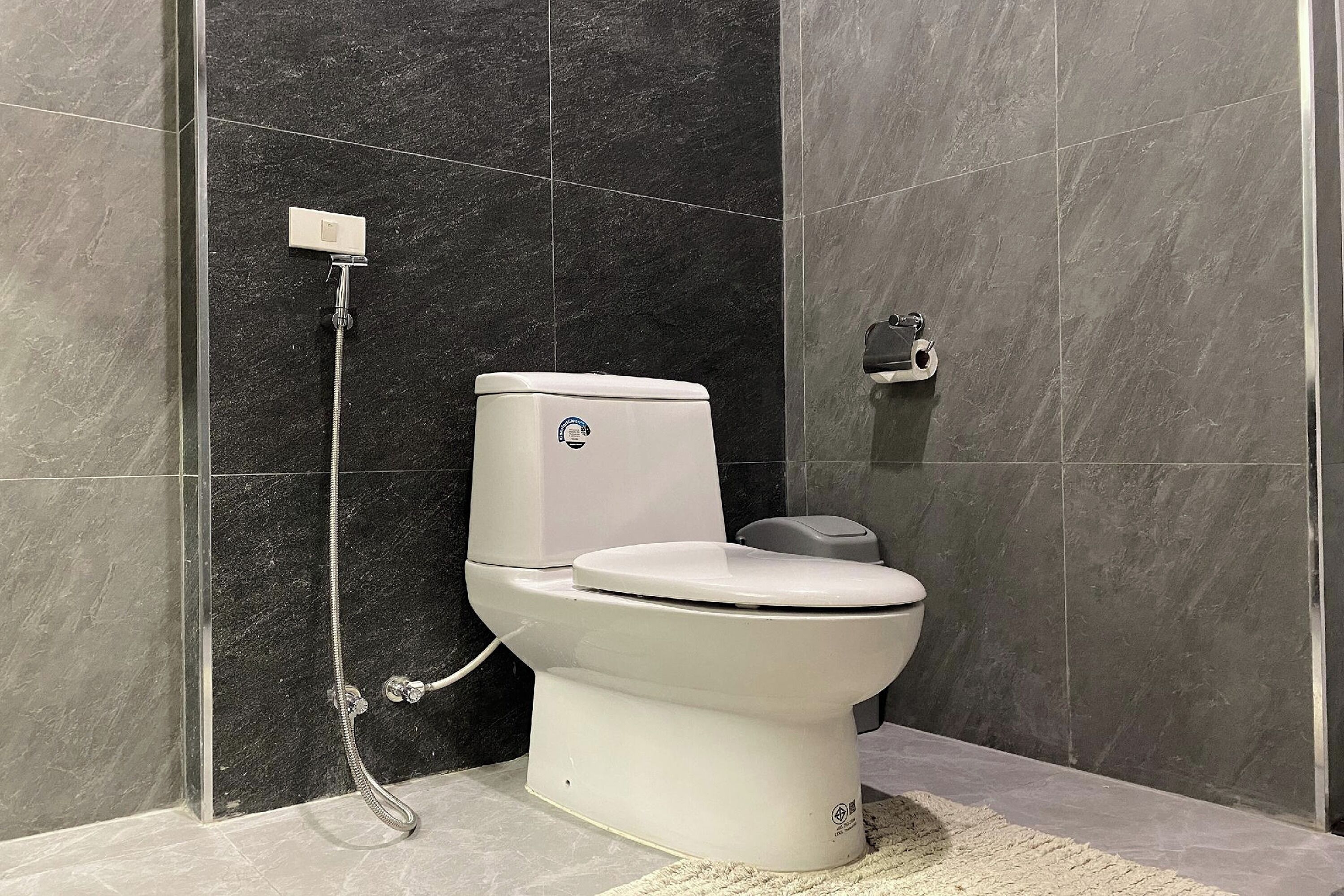 Un baño moderno con inodoro blanco, cabezal de ducha manual y un bidé de pared.