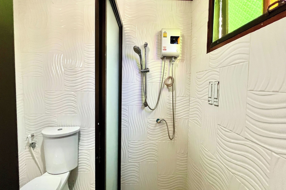 A bathroom with a toilet, a wall-mounted shower unit, and a textured wall design.