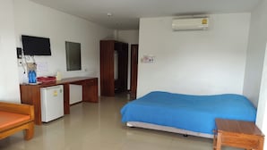 Une chambre d’hôtel équipée d’un lit, d’un bureau, d’une chaise, d’un petit réfrigérateur, d’un téléviseur fixé au mur et d’un appareil de climatisation.