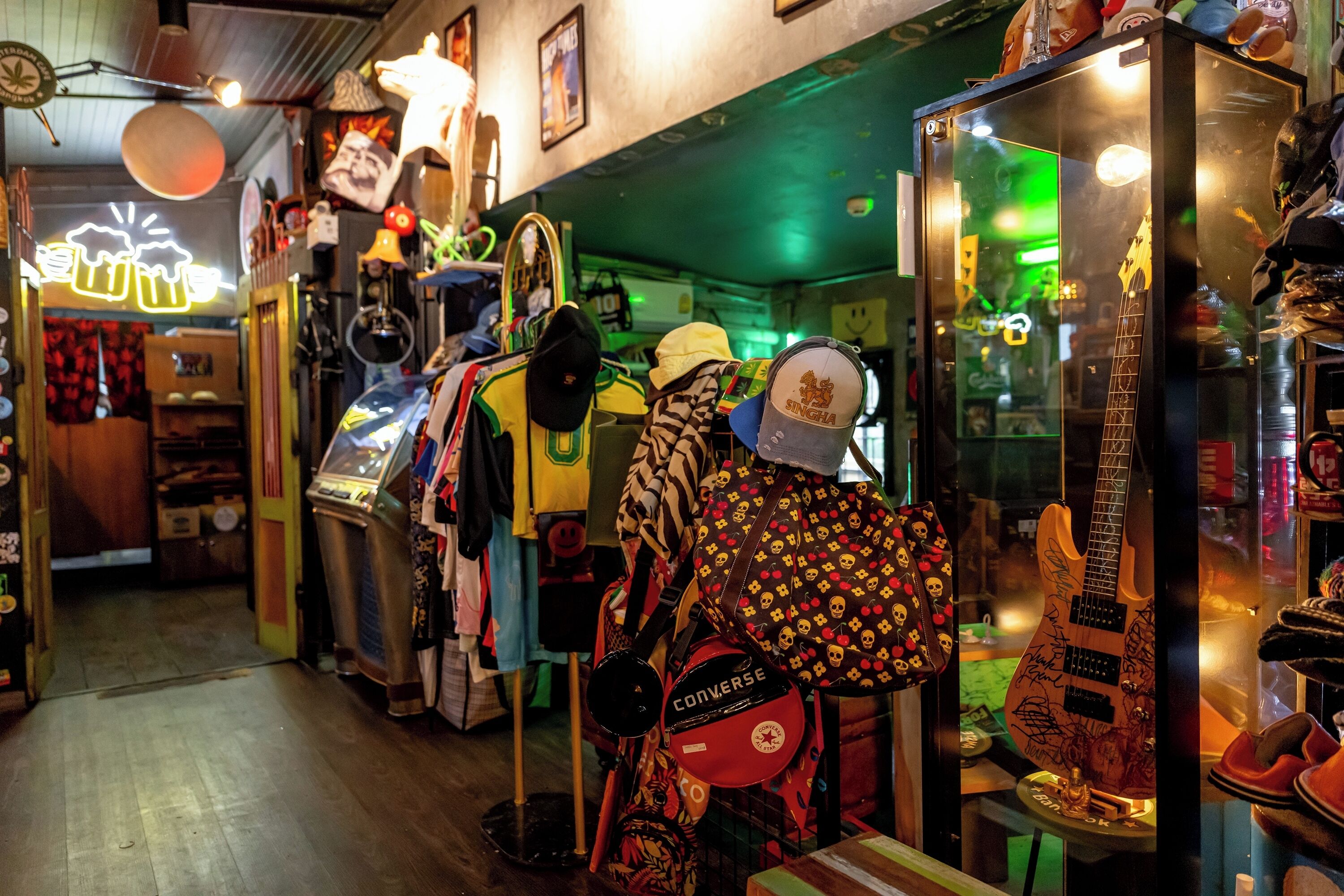 A narrow corridor with various items on display, including a guitar and a mannequin with a patterned bag.