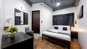 Une chambre d’hôtel comprenant un lit, une table de chevet, une chaise, un bureau et un vase de fleurs.