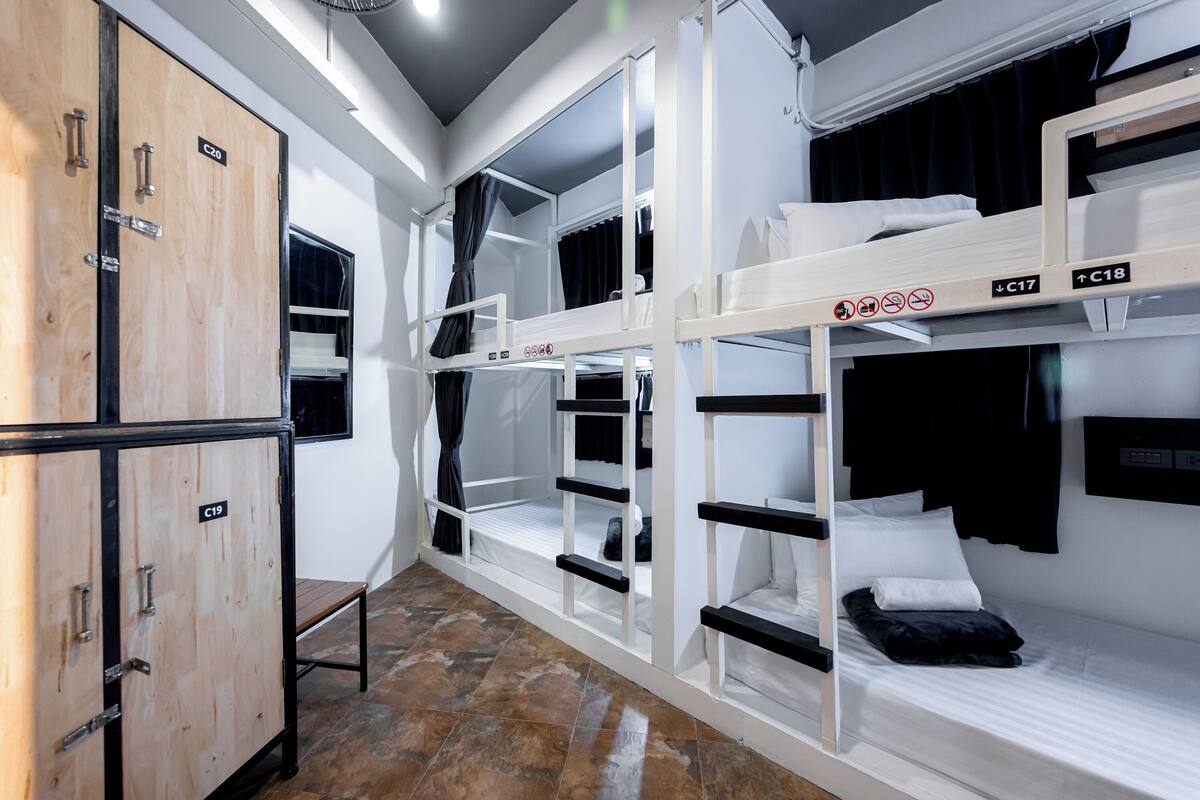 Une chambre de dortoir avec des lits superposés, une armoire en bois et un petit banc.