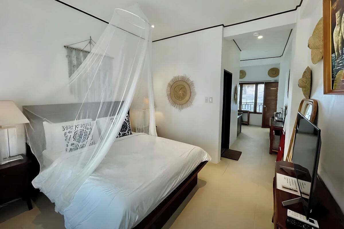 A modern hotel room with a bed, a nightstand, a bedside table, a TV, and a mirror.