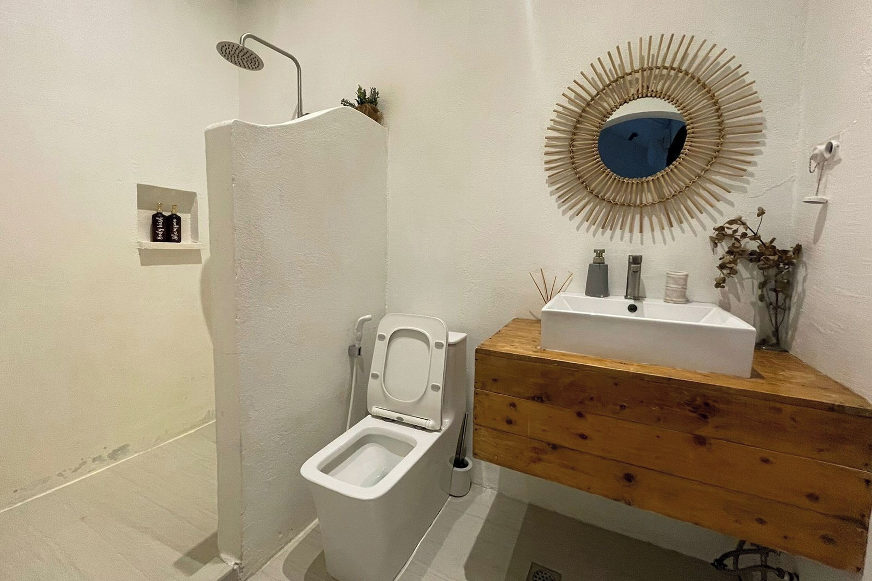 A bathroom with a toilet, a shower, a sink, and a mirror.