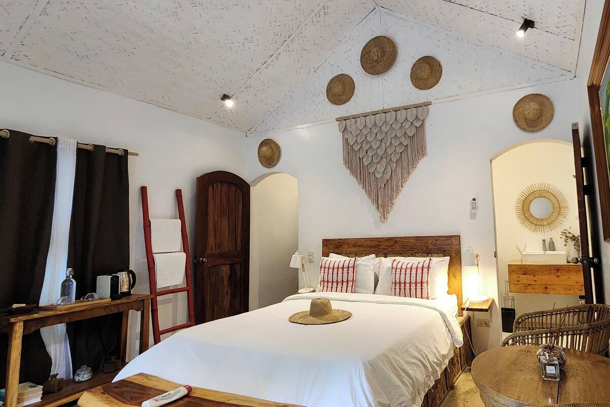 A neatly arranged bedroom with a bed, bedside table, lamp, and a small round table with a chair.