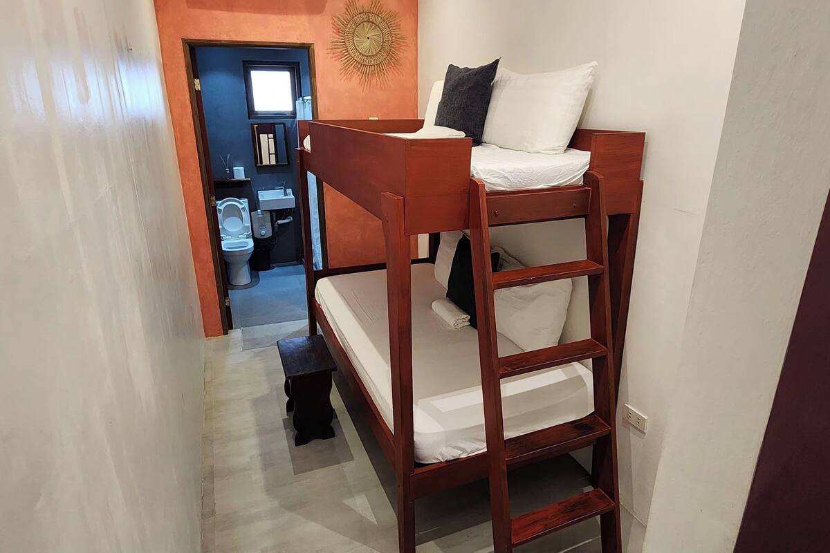 A bunk bed with a ladder, a small bedside table, and a wall-mounted shelf with toiletries.