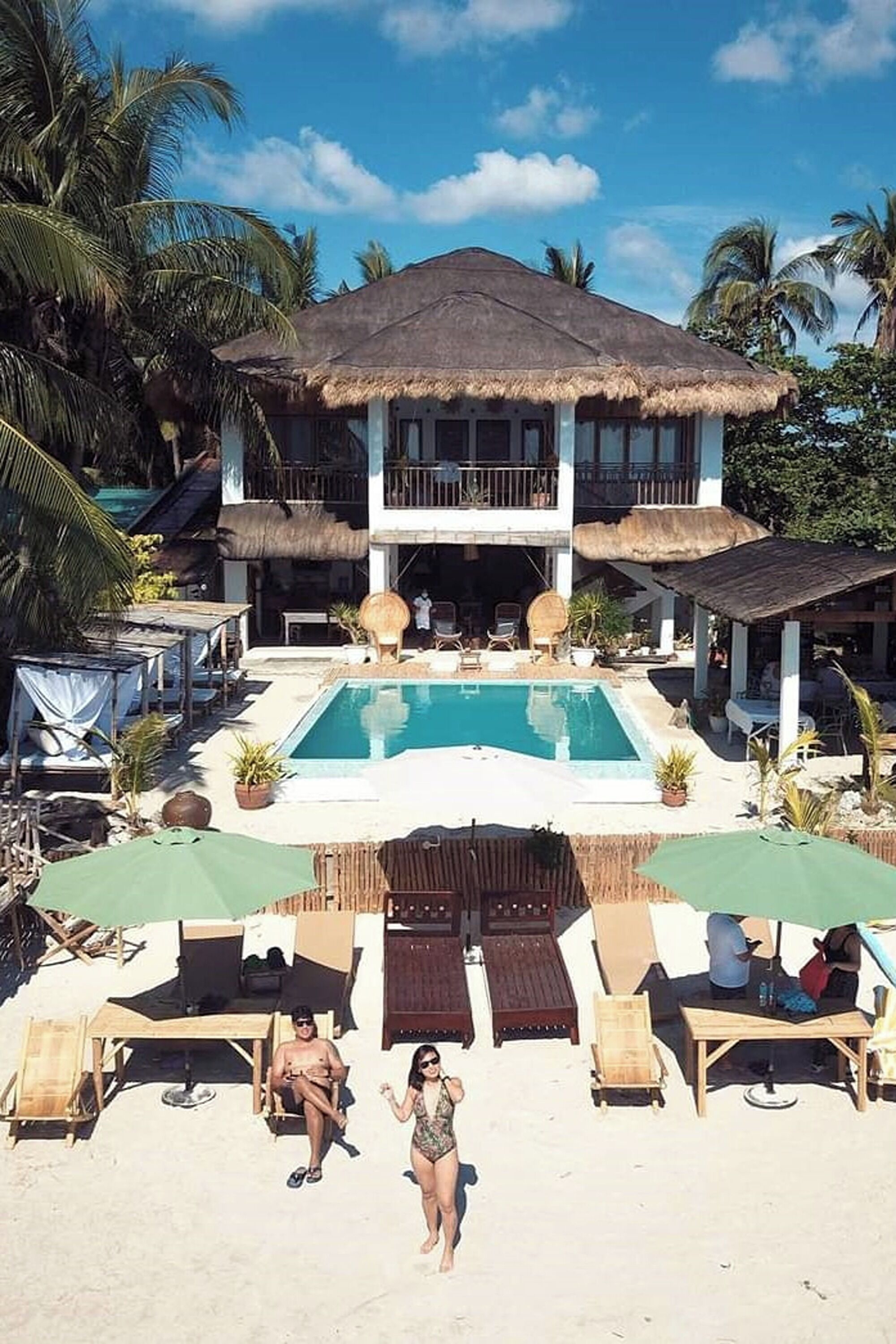 Un resort con piscina, sillas de descanso y un edificio de techo de paja.