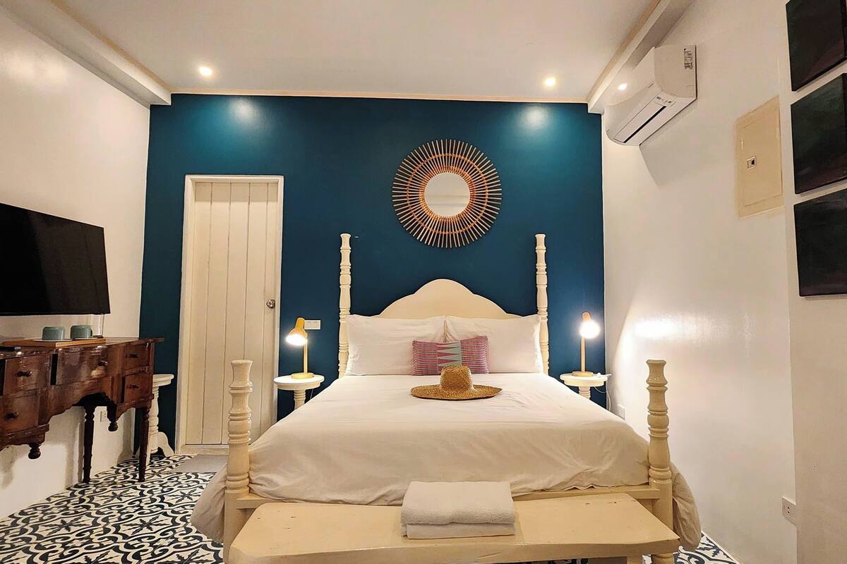A bedroom with a bed, bedside tables, a mirror, and a television.