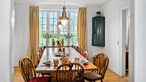 Un comedor con una larga mesa de madera, rodeada de sillas de madera con asientos acolchados.