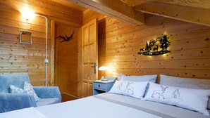 Une pièce de cabane en bois comprenant un lit, une chaise, une table de chevet et une lampe fixée au mur.