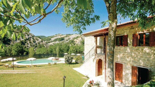 A stone building with a pool, surrounded by a grassy lawn and trees. - Apartment in Marche near Urbino and Pool (Apecchio)