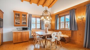 A wooden interior with a dining table, chairs, a chandelier, and a view of the outdoors. - Chalet in Kitzbühel near Ski Lifts (Kitzbühel)