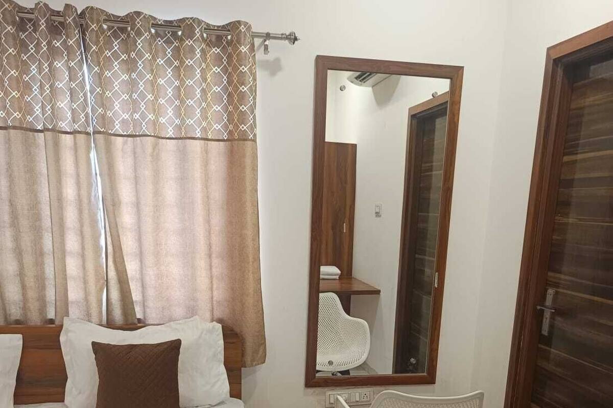 A bedroom with a bed, a chair, a mirror, and a wardrobe.