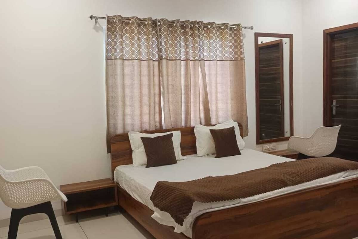 A bedroom with a wooden bed, a chair, a bedside table, and a ceiling fan.
