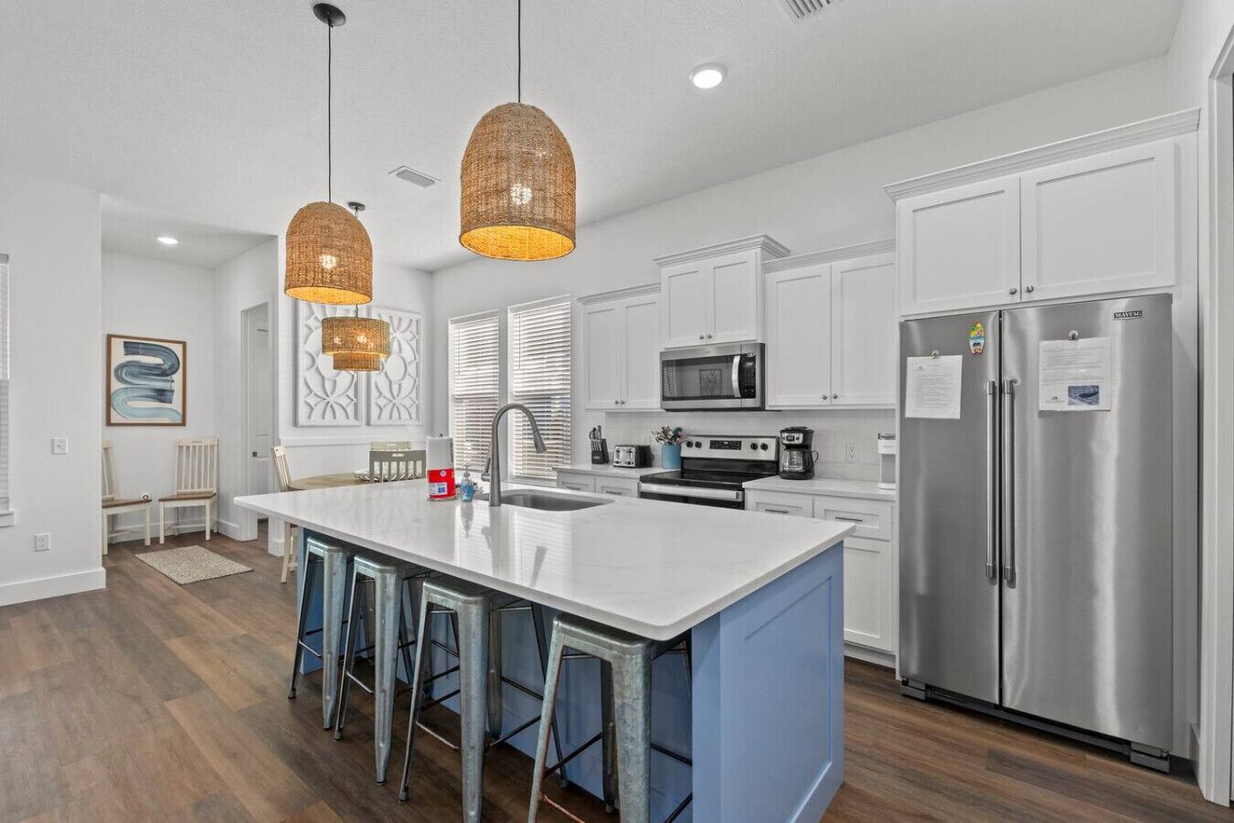 A modern kitchen with a central island, stainless steel appliances, and pendant lighting.