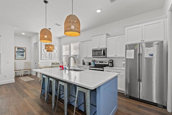A modern kitchen with a central island, stainless steel appliances, and pendant lighting.