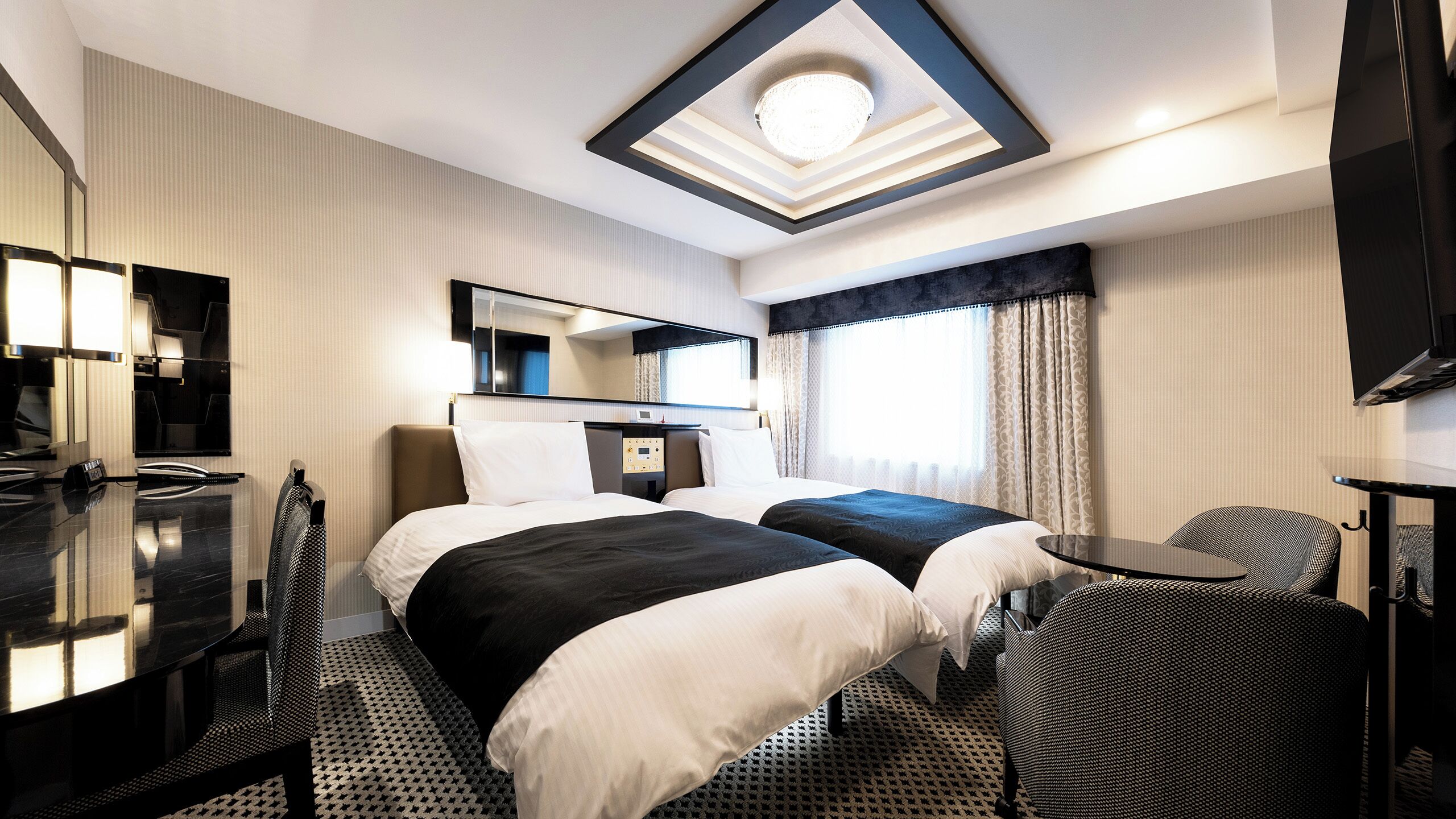 Ein Hotelzimmer mit Bett, Schreibtisch, Stuhl, Fernseher und Deckenleuchte.