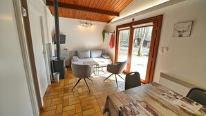 A cozy room with a wooden ceiling, a sofa, two chairs, a table, and a large window.