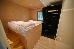 A compact room with a bed, a small window, and a black wardrobe.