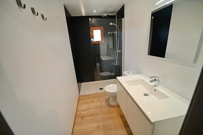 A modern bathroom with a shower, toilet, and sink.
