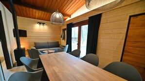 Een houten interieur met een eettafel en stoelen, een bank en een televisie.