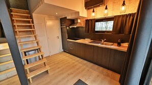 A compact kitchen with wooden flooring, a built-in stove, and pendant lighting.