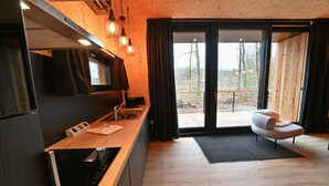A modern kitchen with a wooden countertop, built-in oven, and a large window with curtains.