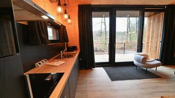 A modern kitchen with a wooden countertop, built-in oven, and a large window with curtains.
