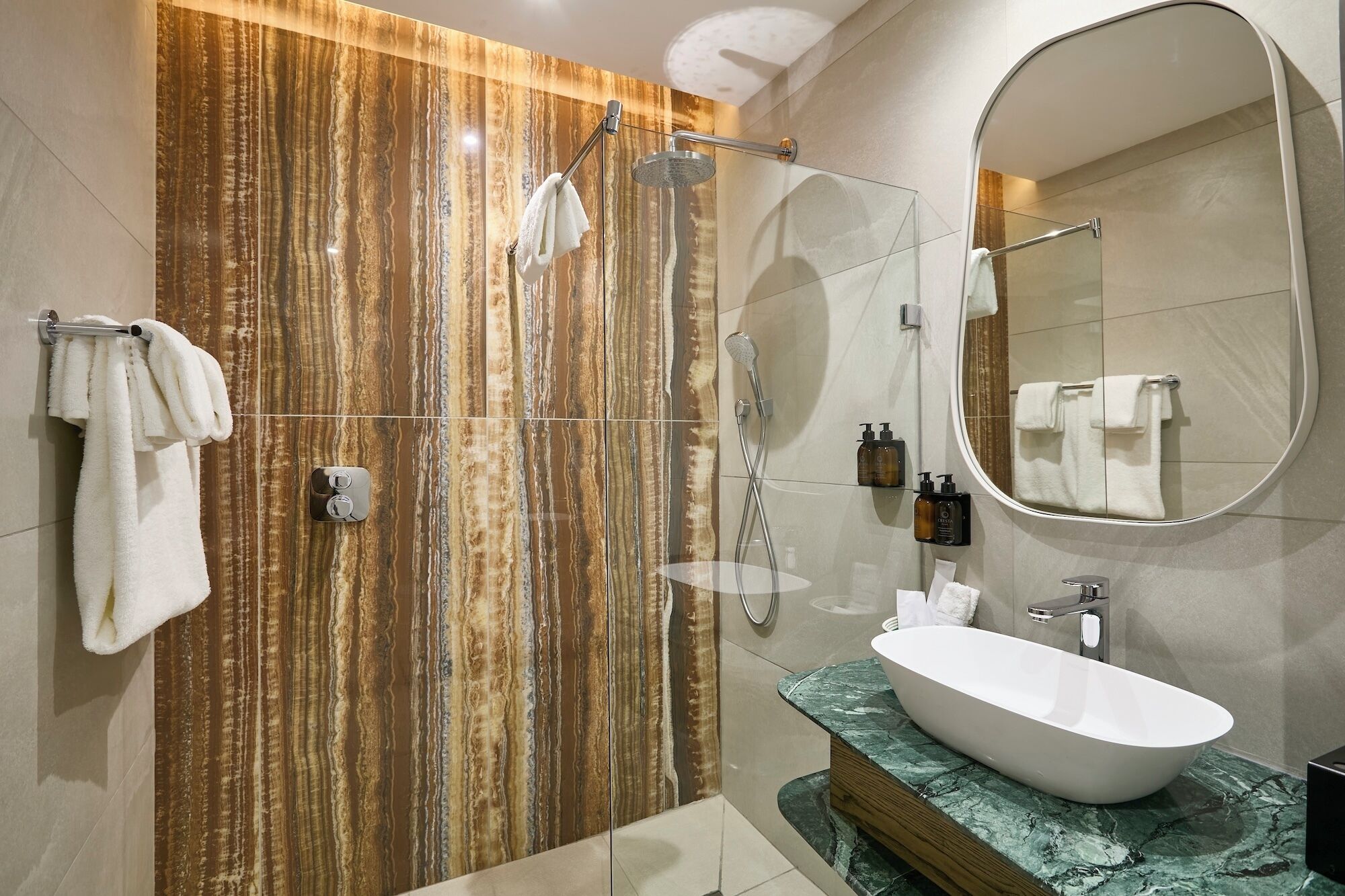 Un baño moderno con un espejo grande, una bañera independiente y una ducha con cabezal de ducha tipo lluvia.