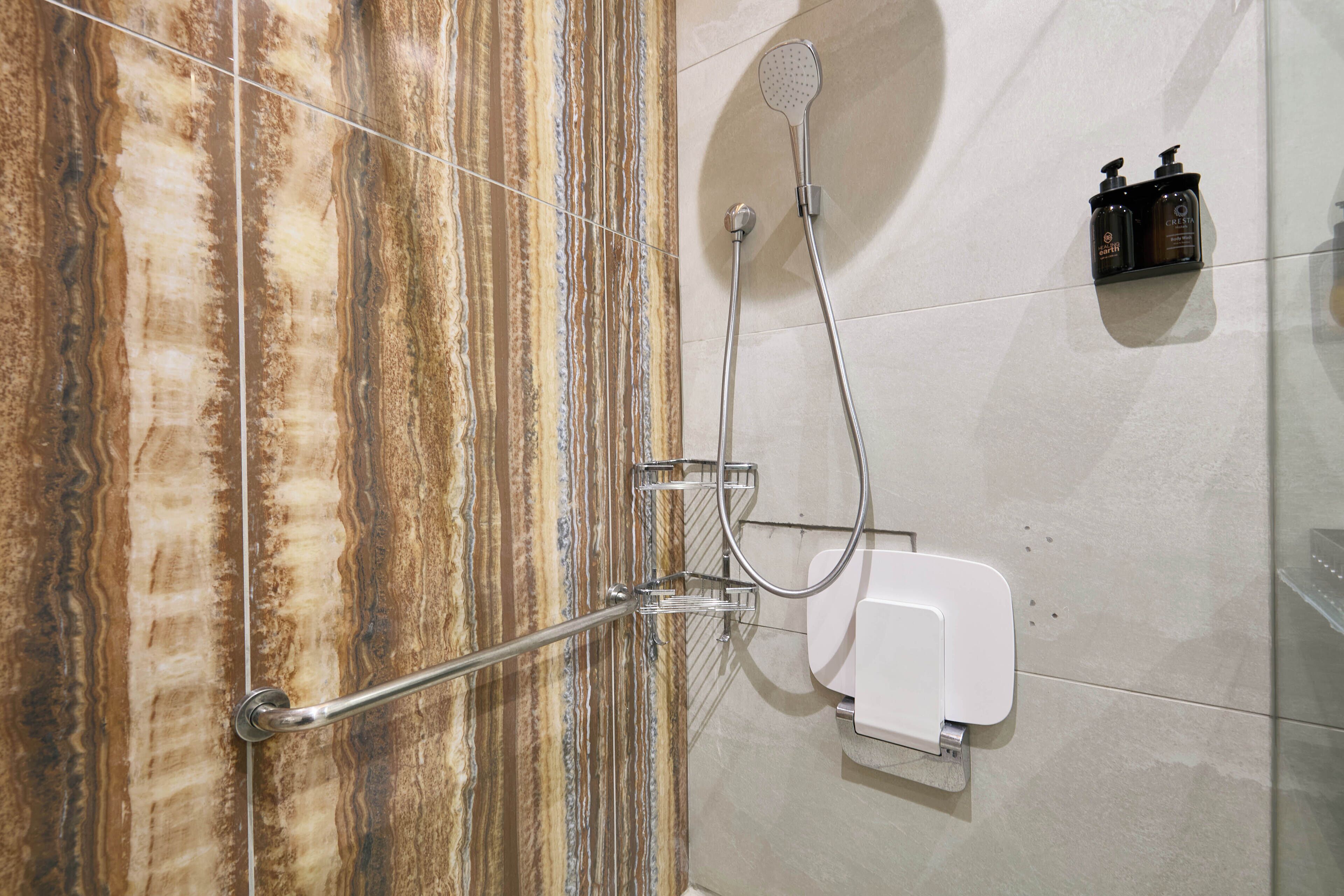 A shower with a handheld showerhead, a handheld showerhead, and a soap dispenser.
