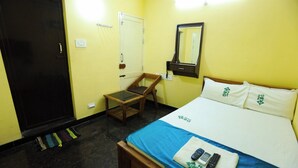 Habitació d'hotel amb llit, escriptori, cadira, armari i mirall.