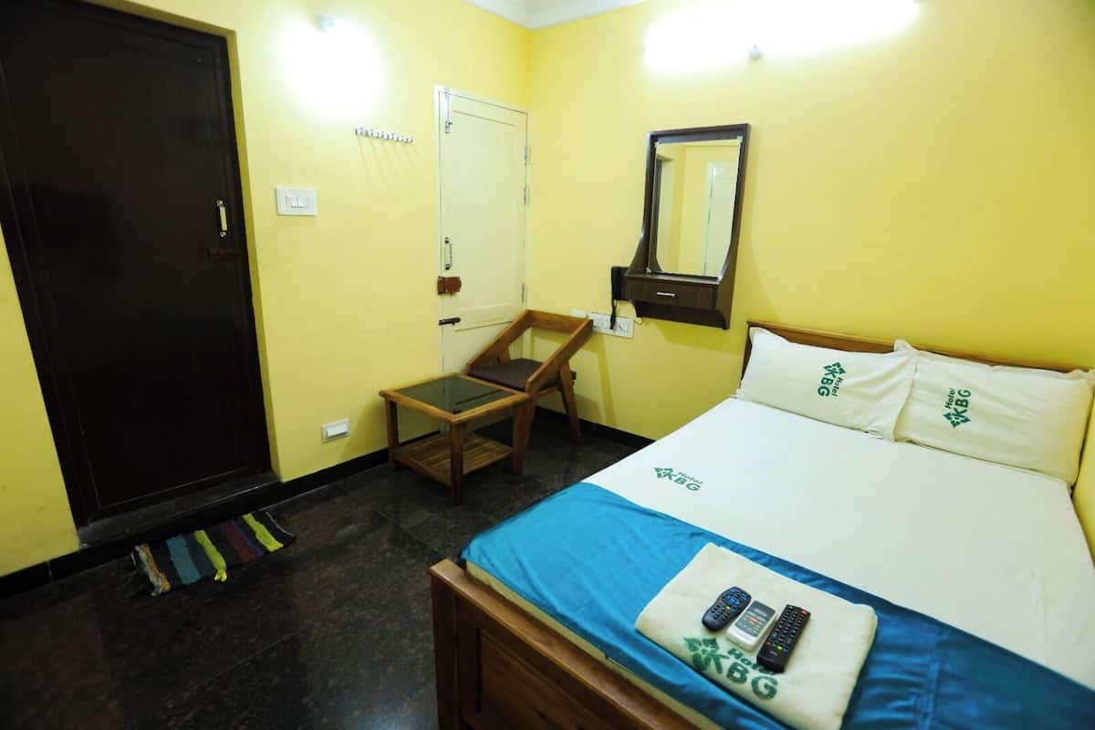 Una habitación de hotel con cama, escritorio, silla, armario y espejo.